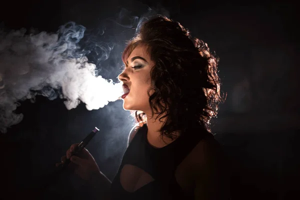 Кудрявая женщина курит кальян в баре или ресторане . — стоковое фото
