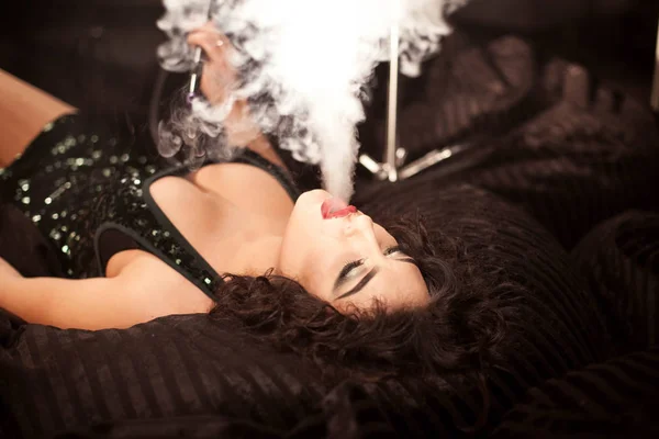 Mujer exhalando humo de narguile. Mujer con vestido brillante . — Foto de Stock