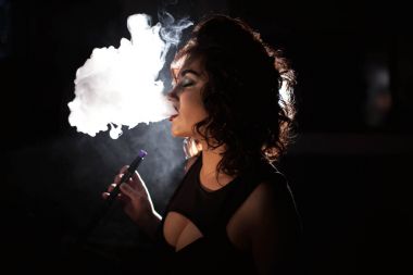 Çekici genç wonam bir duman bulutu exhales. Kıvırcık saçlı kadın.