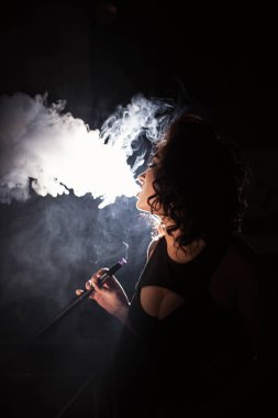 Derin yaka drees sigara nargile giyen kıvırcık saçlı çekici kadın.