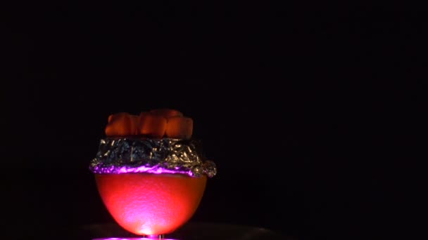 Composition du bol coloré rempli de morceaux de charbons de narguilé sur le fond noir .