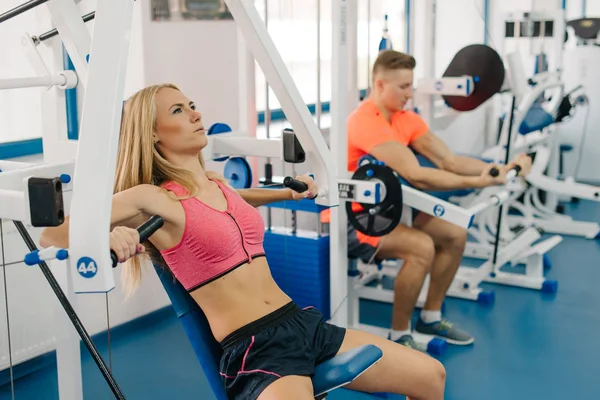Hübsche Frau und starker Mann beim Training im Fitnessstudio. Paar macht Übungen für Arme. perfekte Körper. — Stockfoto