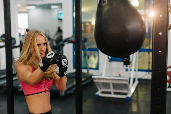 Una joven entrenando en el saco de boxeo. concepto de deporte, fitness, artes marciales y personas — Foto de Stock