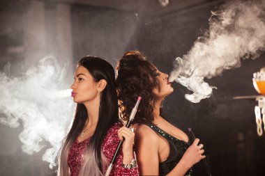 Kızlar arka arkaya bir bar veya bir Restoran Sigara nargile daimi.