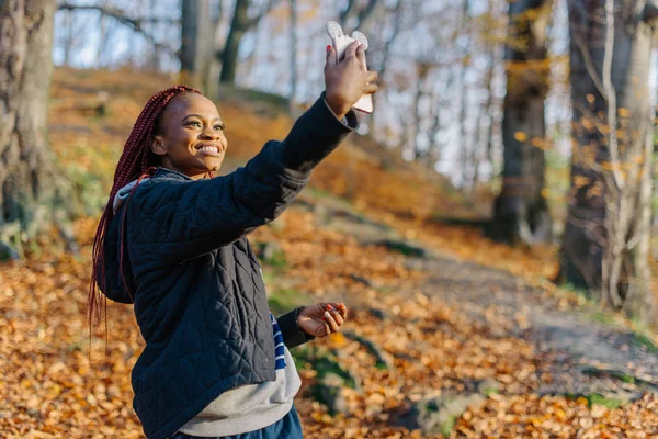 Atraente mulher bonita fazendo selfie no parque de outono. Menina africana sorrindo na foto — Fotografia de Stock