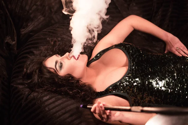 Mujer acostada en bolsas blandas y exhalando una nube de humo de narguile . — Foto de Stock
