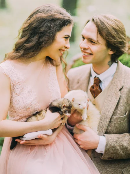 Het portret van de close-up kant van de schattige jonggehuwde paar kijken naar elkaar en de kleine fretten houden op het bos achtergrond. — Stockfoto