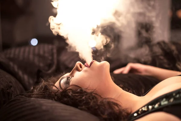 Zbliżenie zdjęcie sexy kobieta palenia fajki. Kobiety z kręconymi włosami i jasny makijaż. — Zdjęcie stockowe