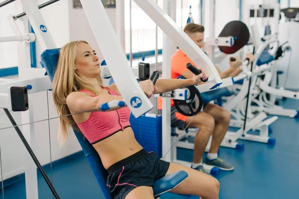 De jeunes athlètes s'entraînent au gymnase. Couple faisant des exercices pour les bras. Corps parfaits . — Photo