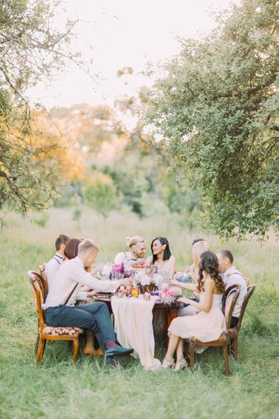 La foto verticale della cena di nozze con gli sposi e gli ospiti che celebrano la cerimonia nella foresta soleggiata . — Foto Stock