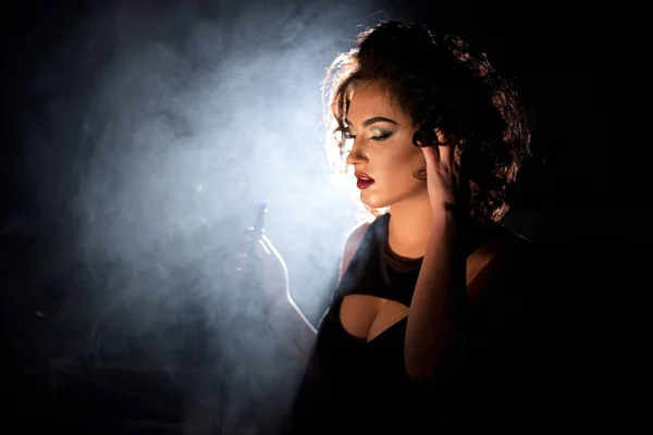 Portrait de femme debout dans une fumée de narguilé. Femme aux cheveux bouclés et aux lèvres rouge foncé . — Photo