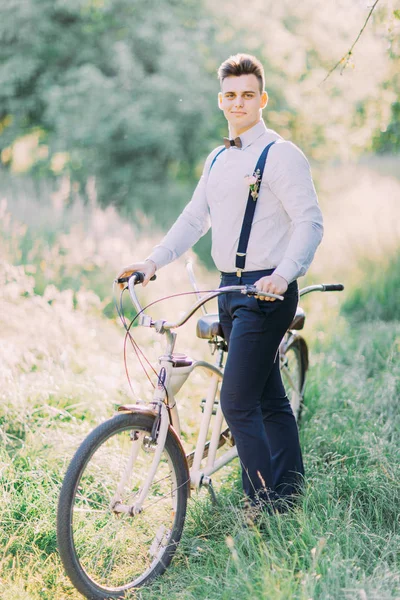 En iyi adam modern mavi elbiseli bicecle güneşli ormandaki taşıyor.