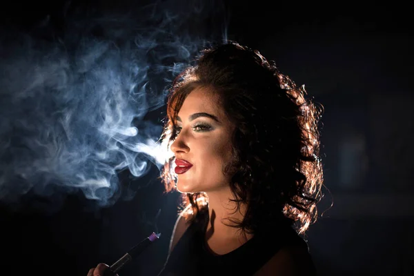 Femme sexy souriante sur fond de fumée. Femme aux cheveux bouclés et au maquillage lumineux . — Photo