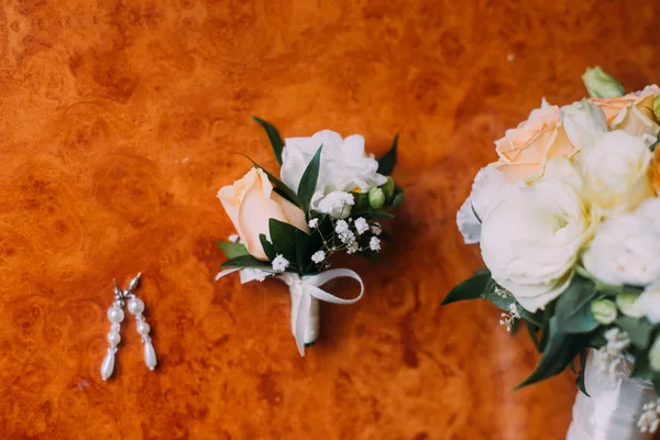 Brincos de noiva, boutonniere e buquê de noiva em fundo de madeira rústica — Fotografia de Stock
