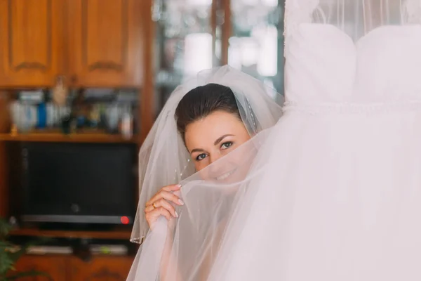 Pengantin yang cantik menyembunyikan wajahnya dengan kerudung cahaya gaun pengantin — Stok Foto