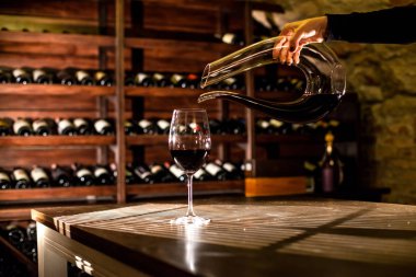 Bir şişe şarap tutan el. Bir cam içine dökme şarap. Şarap kasa konumu.