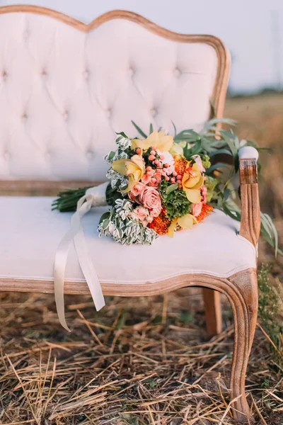 The side bouquet consisted of the colourful roses lying on the wide modern sofa placed in the field. — Stock Photo, Image