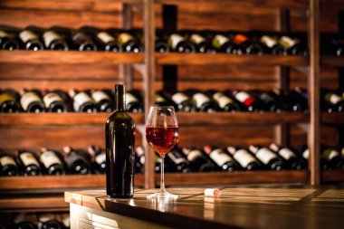 Şişe ve bardak kırmızı şarap ahşap bir masa üzerinde yer dolu. Şarap kasa konumu.