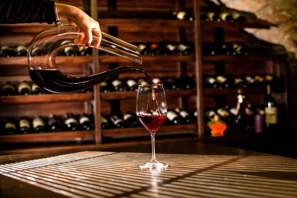 Расположение винного хранилища. Вино, наливаемое в бокал из фигурной винной бутылки . — стоковое фото