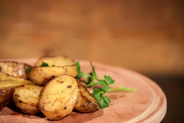 Grilled tasty potato placed on a wooden board together with herbs. — Stock Photo, Image