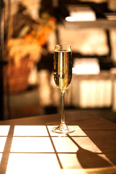 Kieliszek szampana placen na drewnianym stole w słońcu. — Zdjęcie stockowe