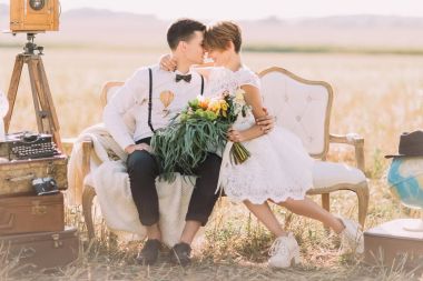 Güzel yakın çekim yatay portresi kafa kafaya kanepede oturan yeni evliler. Gelin renkli düğün buket alanın arka plan düzenliyor.