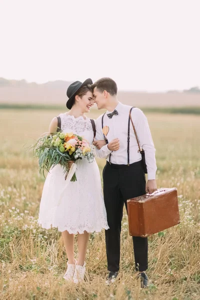A bela vista do vintage recém-casados vestidos de pé nariz a nariz um para o outro no fundo do campo ensolarado . — Fotografia de Stock