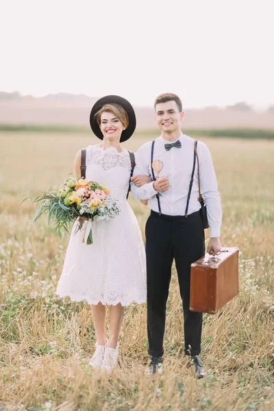 Mutlu yeni evliler alanında vakit önden görünümü. Adam vintage elbise taşıyor ise gelin renkli buket tutuyor.