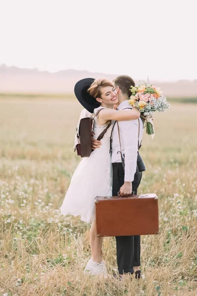 Het portret van de mooie kant van de gelukkig vintage jurk newlyweds knuffelen in het zonnige veld. — Stockfoto