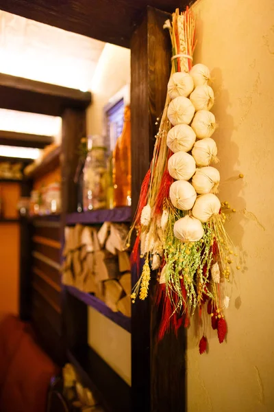 The close-up photo of the artificial onions and grass hanging on the wooden beam in the lovely cafe. — Stock Photo, Image