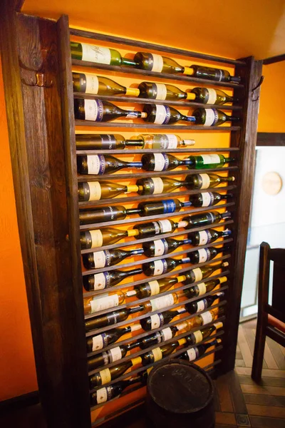 The close-up view of the wooden slelves full of wine bottles placed in the cafe. — Stock Photo, Image