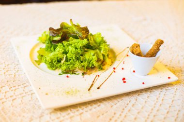 Yakın çekim yan görünüm kuru ekmek ve salata sosu ile dekore edilmiş ve beyaz masanın üzerine yerleştirilen.