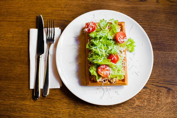 De bovenstaande samenstelling van het voedsel. De Belgische wafels met groenten zoals tomaten, salat en kaas. — Stockfoto