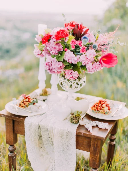 A vista vertical do conjunto de mesa de casamento consistia no buquê de flores, bolo e velas nas montanhas. . — Fotografia de Stock