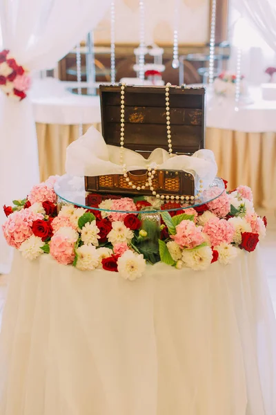 Caixa de madeira do casamento decorada com contas colocadas na mesa coberta com flores coloridas . — Fotografia de Stock