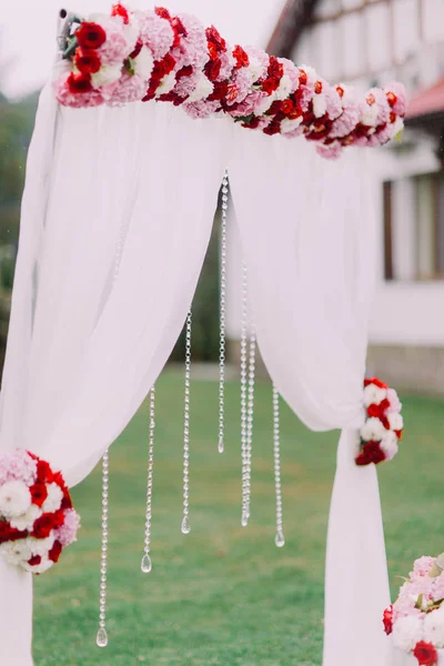 Vista lateral del arco de la boda decorado con flores de colores y cuentas colgantes . — Foto de Stock