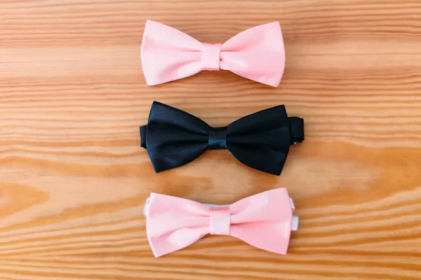 Two pink bow-ties and one black lying on the floor. — Stock Photo, Image
