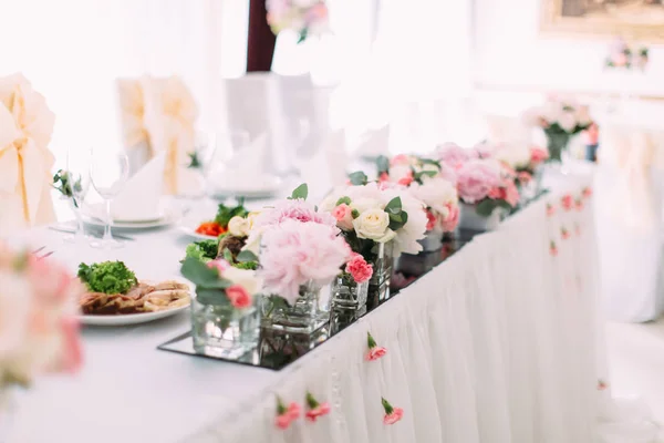 Vista lateral de las pequeñas flores rosadas en los mini-jarrones en el conjunto de mesa de la boda . —  Fotos de Stock