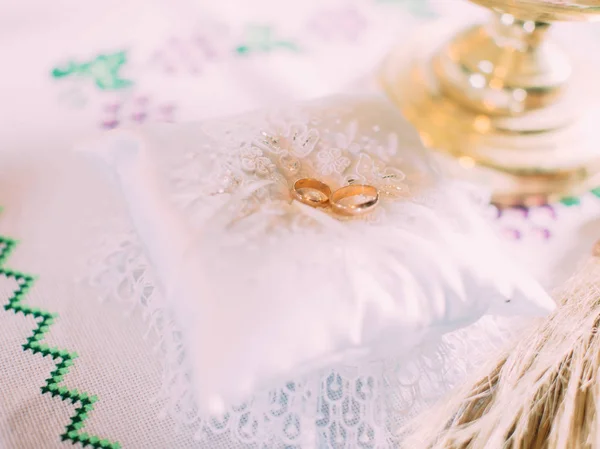 Gouden trouwringen liggen op het witte kleine kussen. — Stockfoto