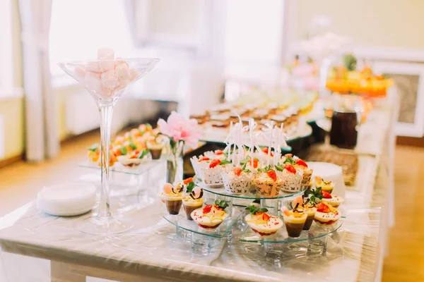 Lezzetli düğün cupcakes büyük vazo içinde pembe şekerleme yaparken tatlı standında döşeme. Düğün masa seti.