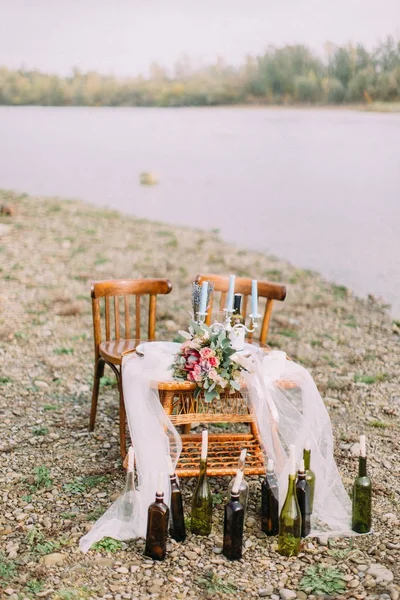 Full-length view of the wedding table set placed on the coast. The wedding bouquet on the woven table. — Stock Photo, Image