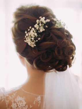 Gelin saç modeli küçük beyaz çiçekler ve dantel ile dekore edilmiş.