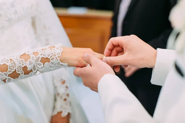 Vista de cerca de la mano del novio poniendo el anillo de bodas en el dedo de la novia . — Foto de Stock