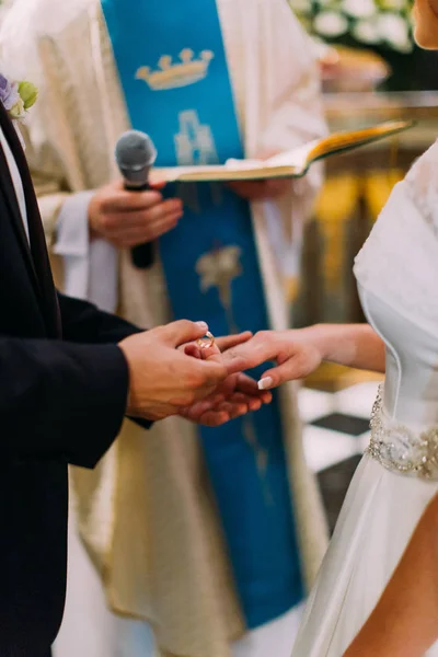 Photo verticale des mains du marié mettant l'alliance sur le doigt de la mariée . — Photo