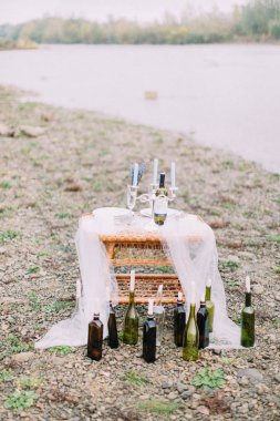 Çok güzel wickered tablo ile mumlar ve şarap şişeleri sahilde şeklinde mum tribünde civarında.