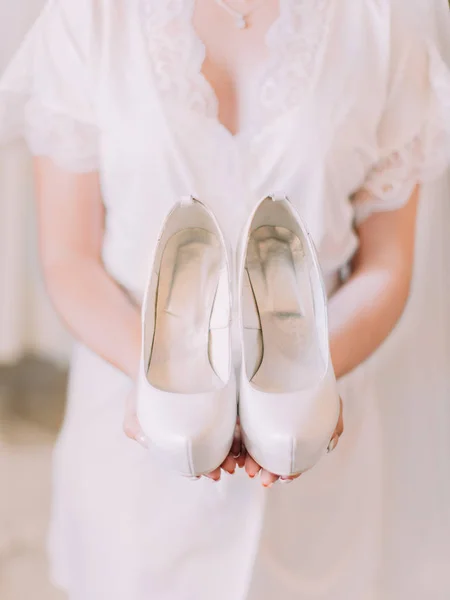 Руки невесты, держащей белые свадебные туфли . — стоковое фото