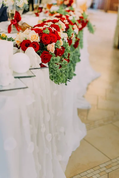 La vista lateral de cerca de las rosas rojas y blancas decoran la mesa de bodas . — Foto de Stock