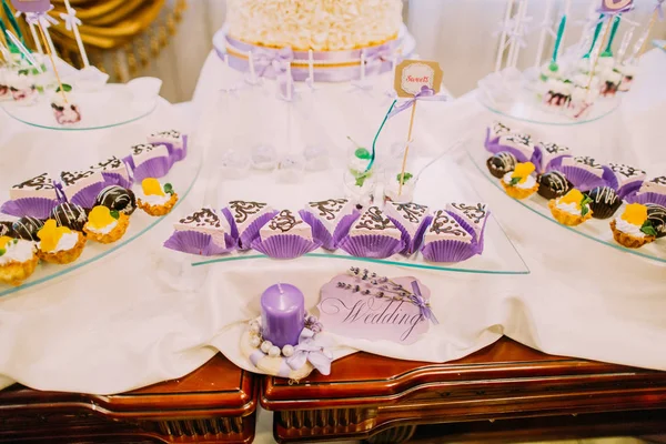 Dessert bar per matrimoni. Vista da vicino delle dolci torte sul tavolo decorate con segni di nozze e candele . — Foto Stock