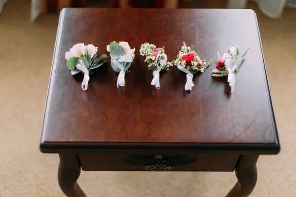 Vista de perto dos cinco boutonnieres de rosas coloridas na mesa . — Fotografia de Stock
