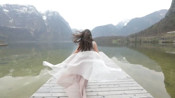 Encantadora mujer activa en el vestido largo es divertirse mientras se balancea y salta en el muelle en las montañas . — Vídeo de stock